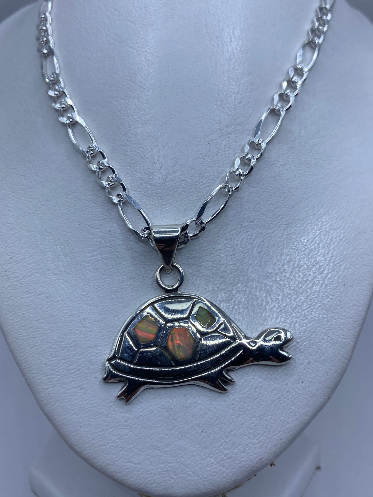 Dije tortuga visto de frente mostrando el ópalo de fuego con tonos rojo y verde