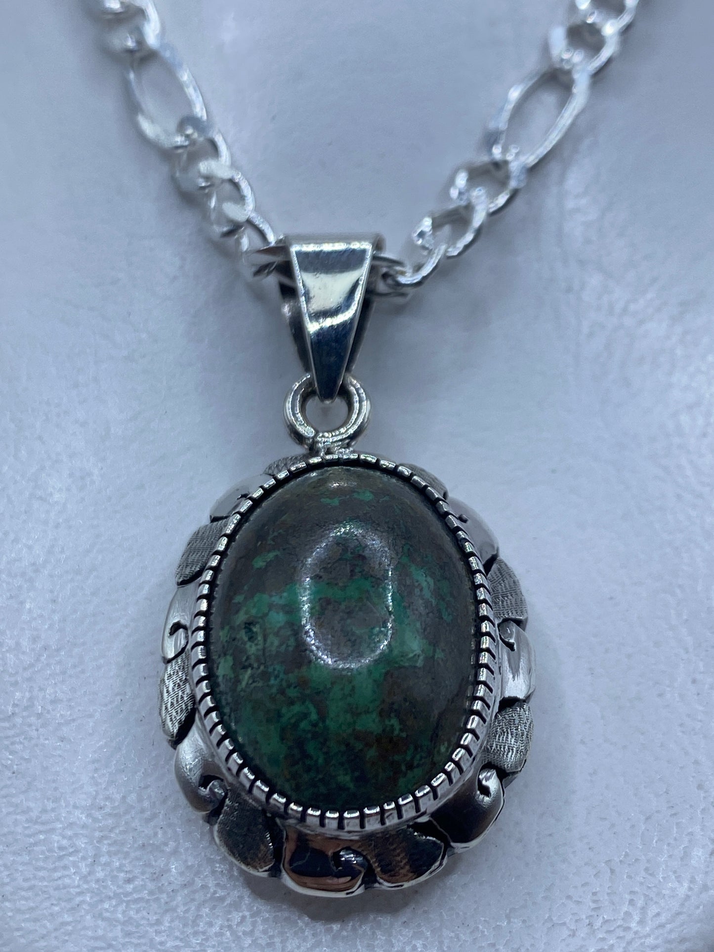 Dije de plata con piedra engastada de 4.9 cm, colgado sobre fondo blanco
