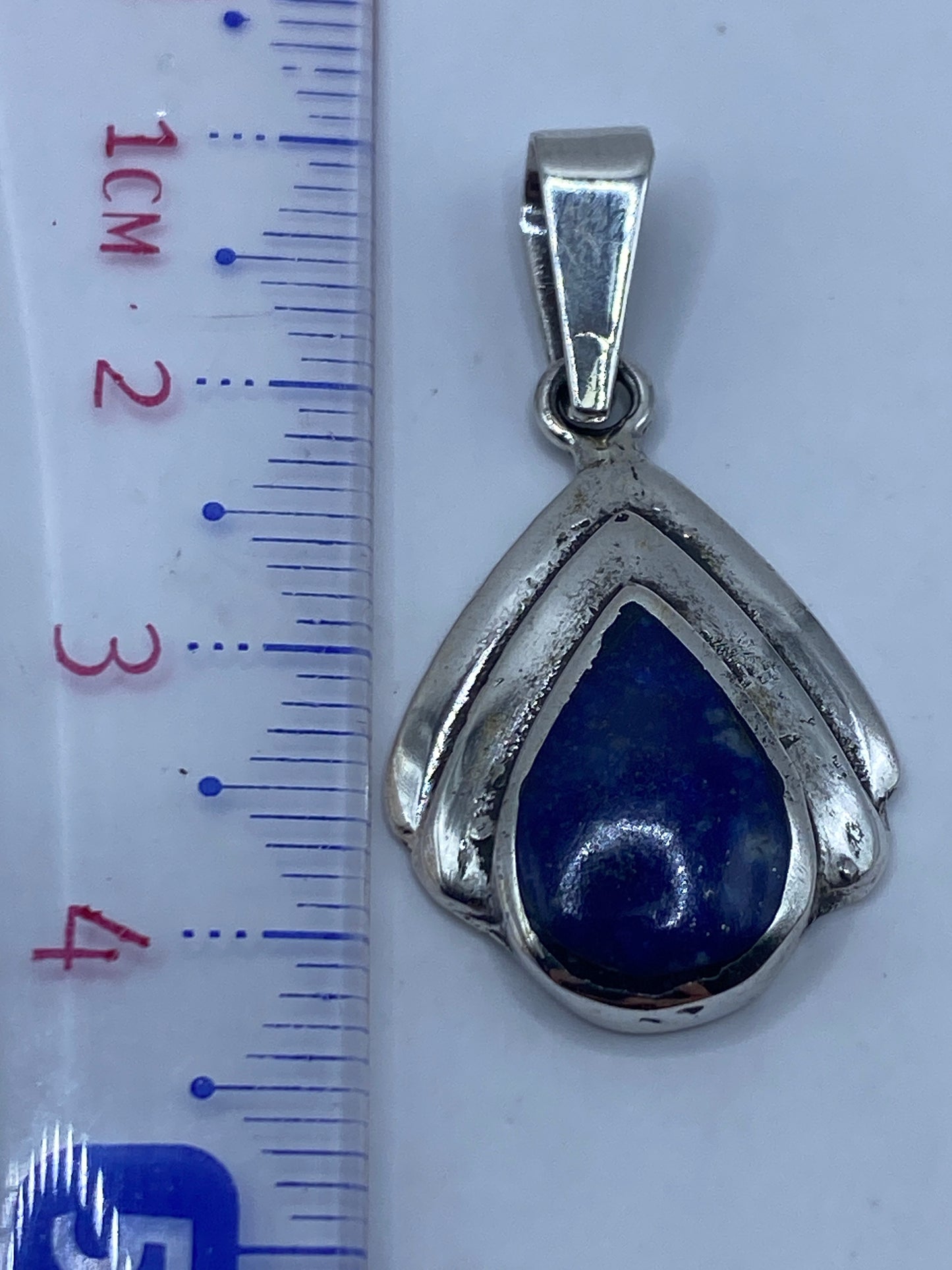 Dije de plata sobre fondo blanco con el sello .925 visible en el engaste