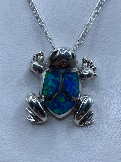 Dije sapo de plata .925 con ópalo de fuego azul engastado, colgando de cadena de plata