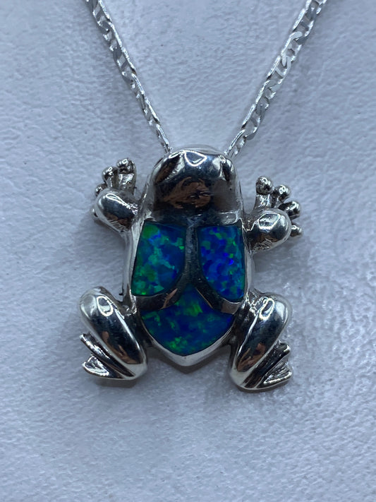 Dije sapo de plata .925 con ópalo de fuego azul engastado, colgando de cadena de plata