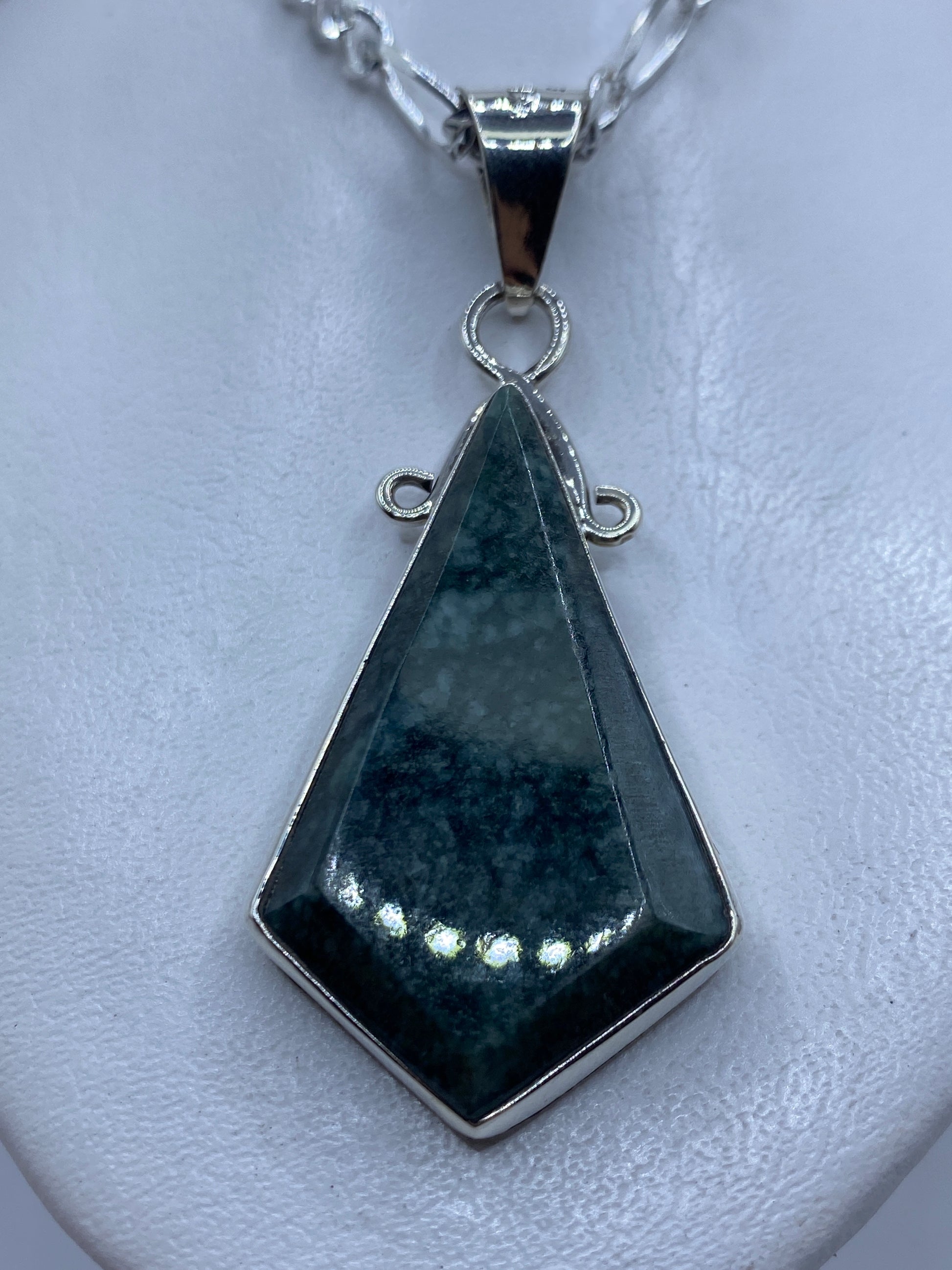 Dije de plata .950 con piedra verde incrustada, forma geométrica alargada, sobre cadena de plata
