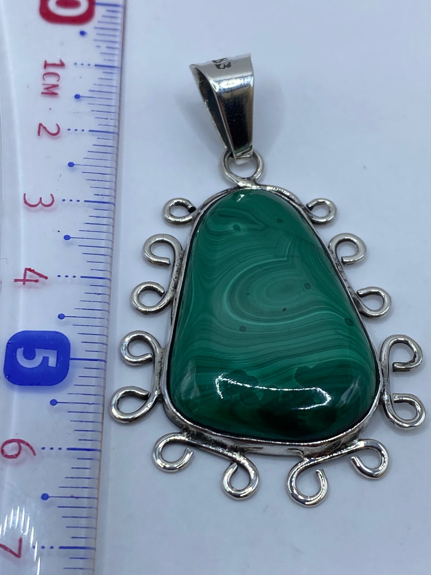 Reverso del dije de plata mostrando el Quinto .950 y espirales ornamentales