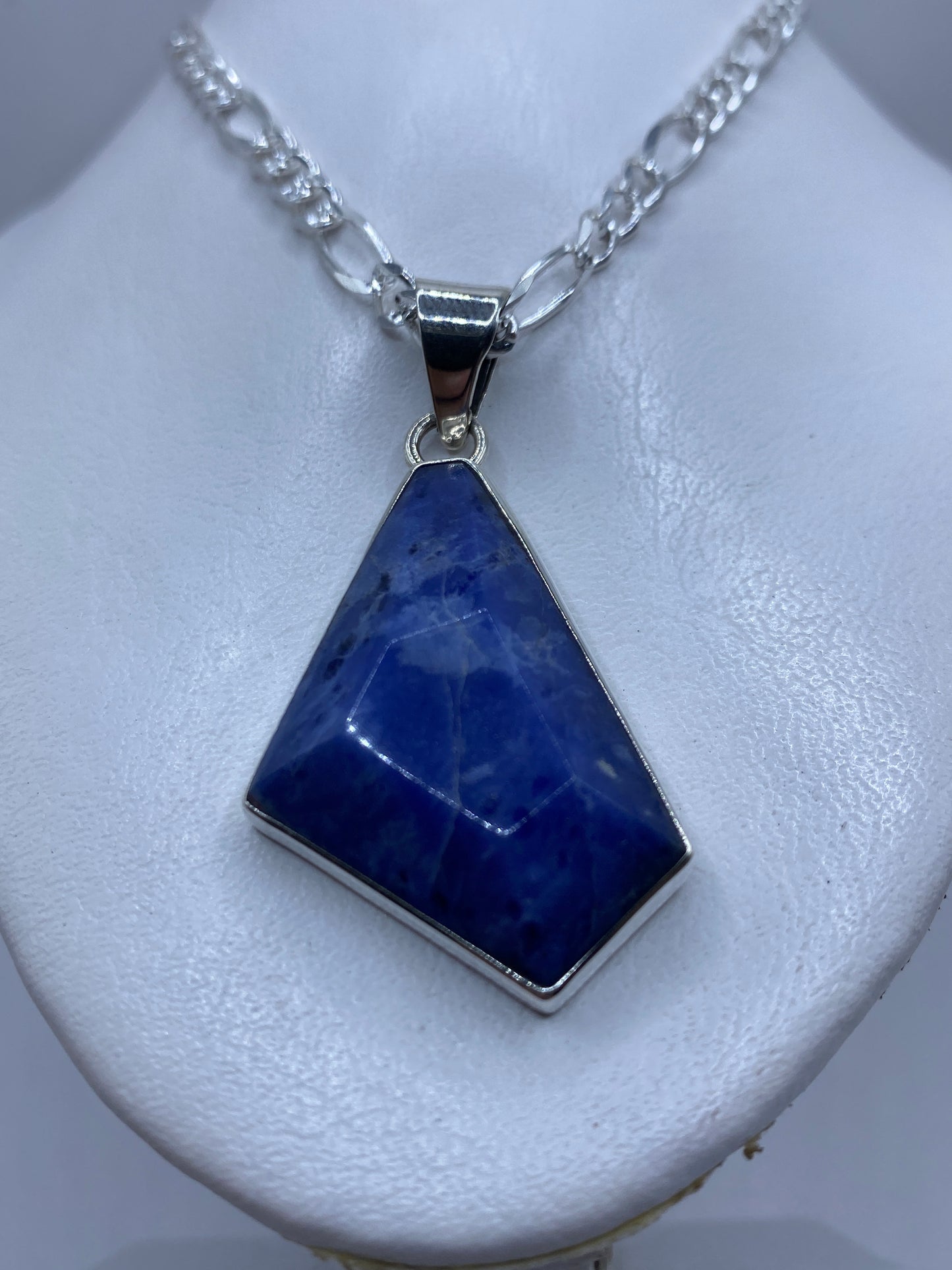 Detalle frontal del dije mostrando la piedra azul y el engaste a mano