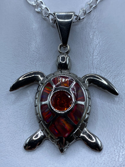 Dije de plata con forma de tortuga marina y ópalo de fuego naranja engastado en el centro