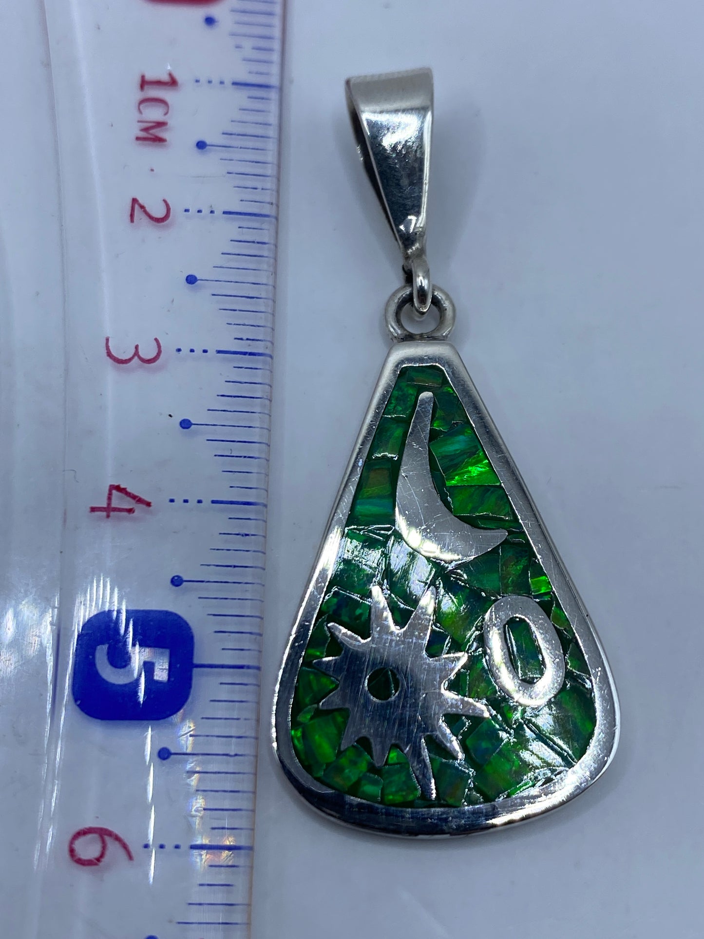Dije sobre regla de medida mostrando 5.8 cm de largo, peso de 7.3 gramos