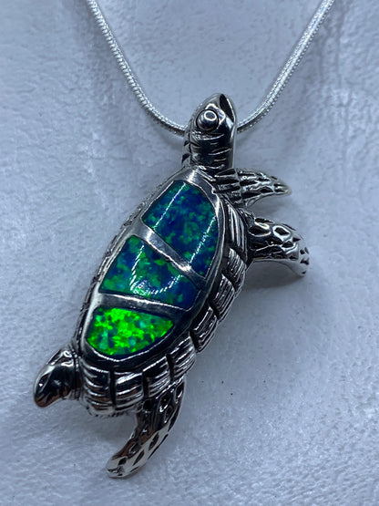 Dije de plata en forma de tortuga con ópalo de fuego azul engastado en el caparazón