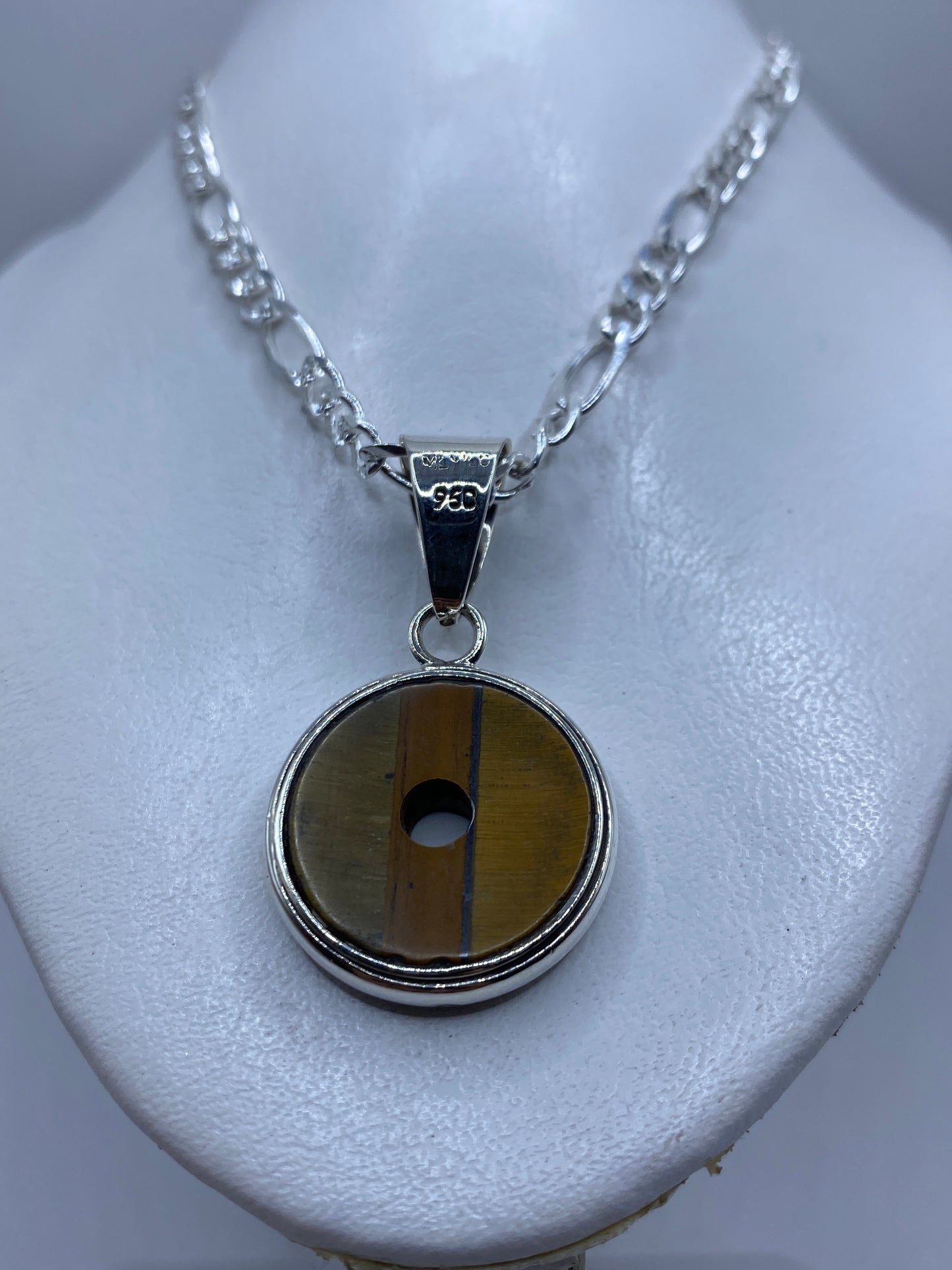 Dije de plata .950 en la mano de una mujer, con vista frontal de la piedra