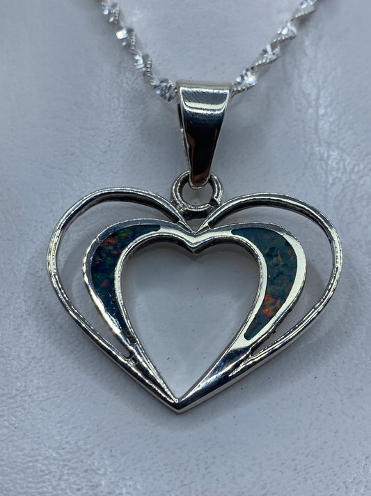 Dije de corazón doble en plata .950 con ópalo de fuego azul, colgado de una cadena plateada