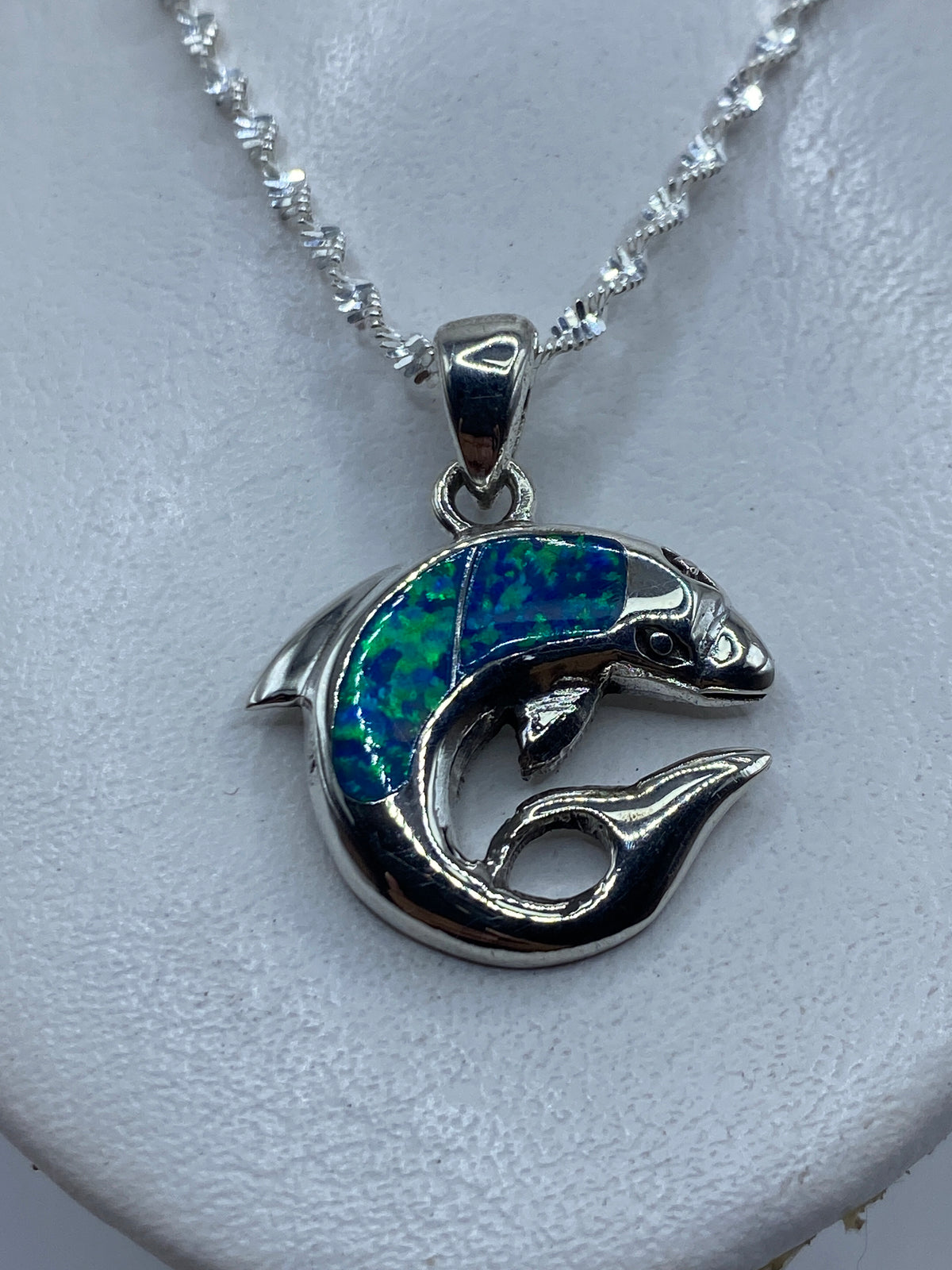 Dije de plata con ópalo de fuego azul verdoso, mostrado con cadena de plata en el pecho