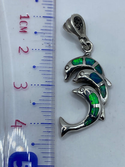 Dije de delfín de 4.3 cm sobre regla métrica, mostrando escala real
