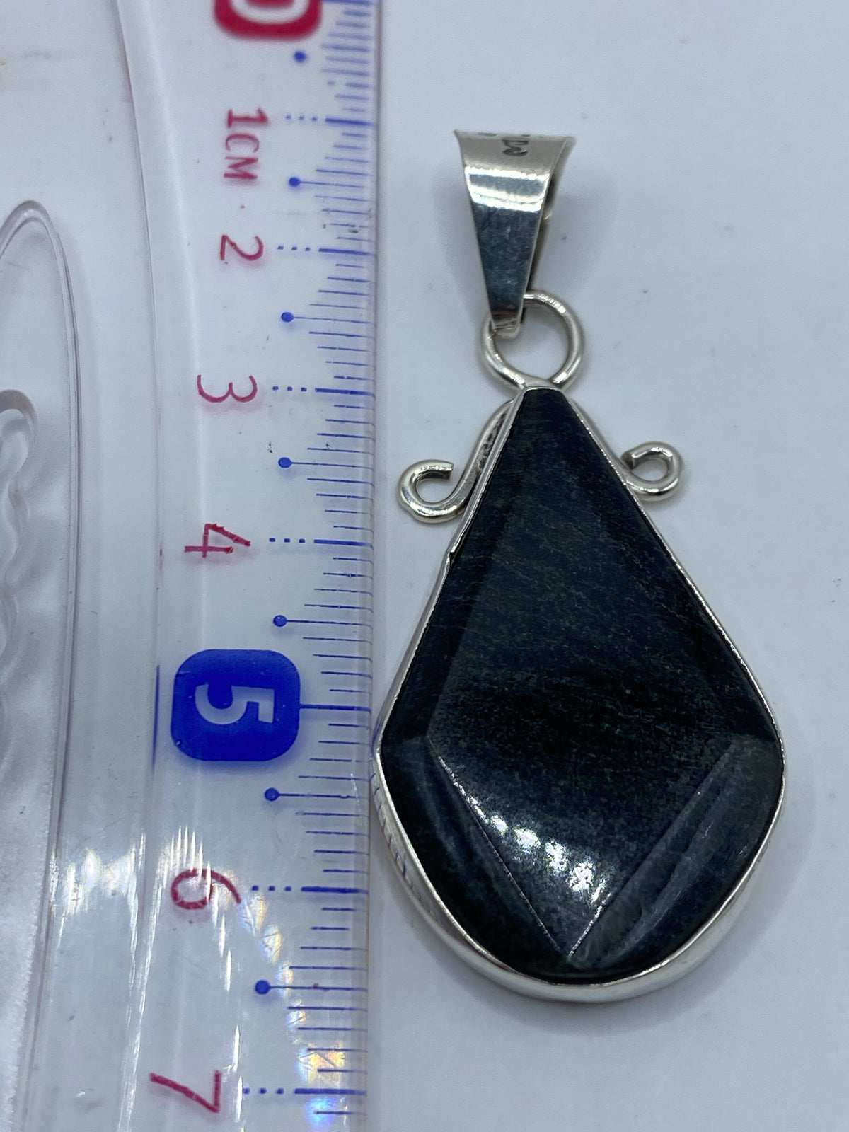 Dije sobre fondo gris mostrando el sello .950 y el tamaño real de 6.4 cm