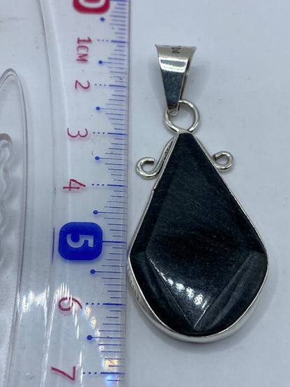 Dije sobre fondo gris mostrando el sello .950 y el tamaño real de 6.4 cm