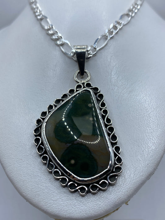 Detalle del engaste a mano de la piedra verde olivo en plata .925, mostrando la filigrana del marco
