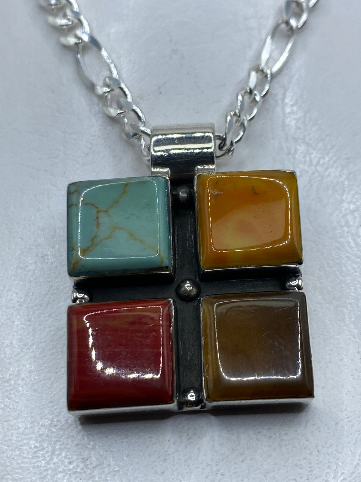 Dije de plata con cuatro piedras naturales (turquesa azul, ámbar, coral rojo, jade) engastadas a mano en Taxco