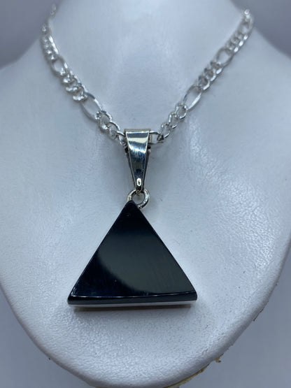 Detalle del ónix negro pulido y el engaste de plata en el dije triangular