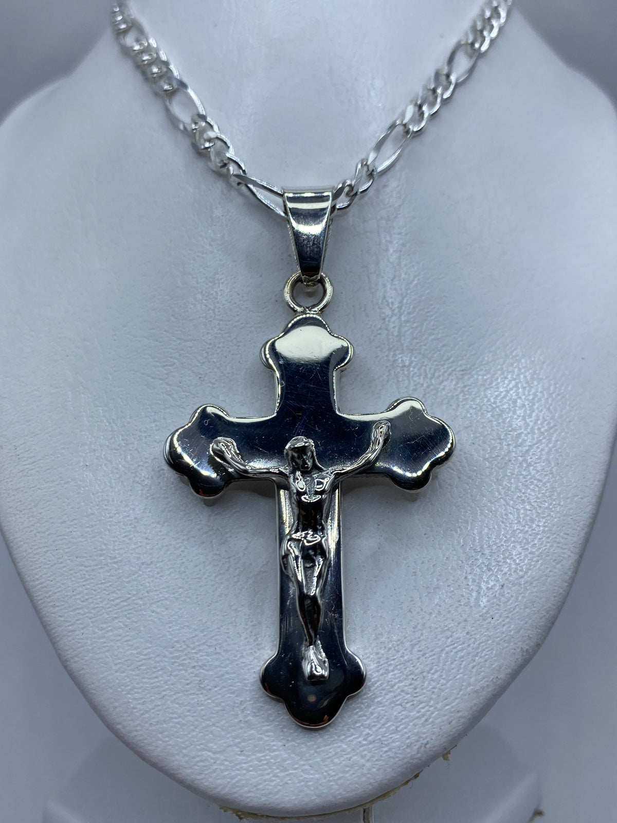 Medida del dije crucifijo de 7 cm junto a una regla, mostrando su tamaño visible