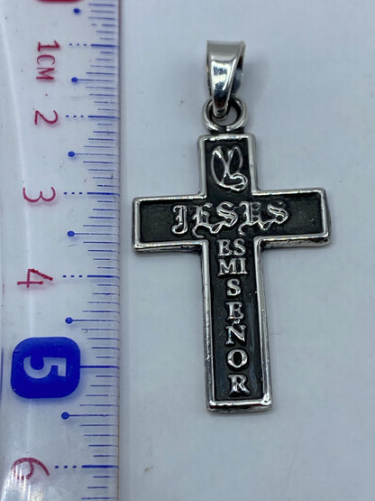 Cruz de plata en la mano, mostrando tamaño real de 5.4 cm