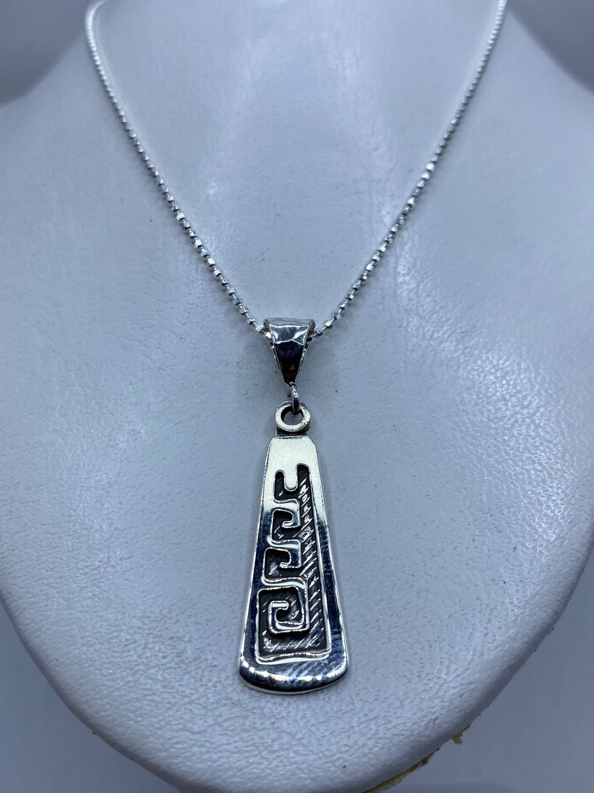 Vista frontal del dije prehispánico mostrando el detalle de las grecas geométricas