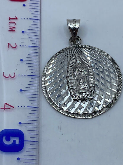 Reverso del dije de plata repujada mostrando el trabajo de martillo y punzón