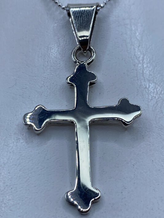Cruz de plata .925 en calado de Taxco, colgada al pecho sobre una blusa blanca