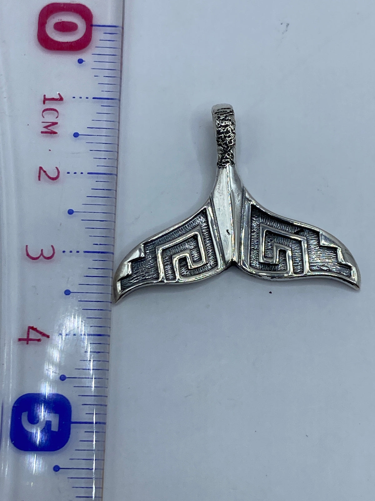 Dije de plata prehispánico visto desde atrás mostrando el acabado pulido del reverso
