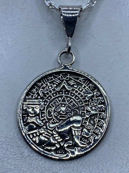 Dije de plata repujado con calendario azteca de frente, sobre cadena de plata