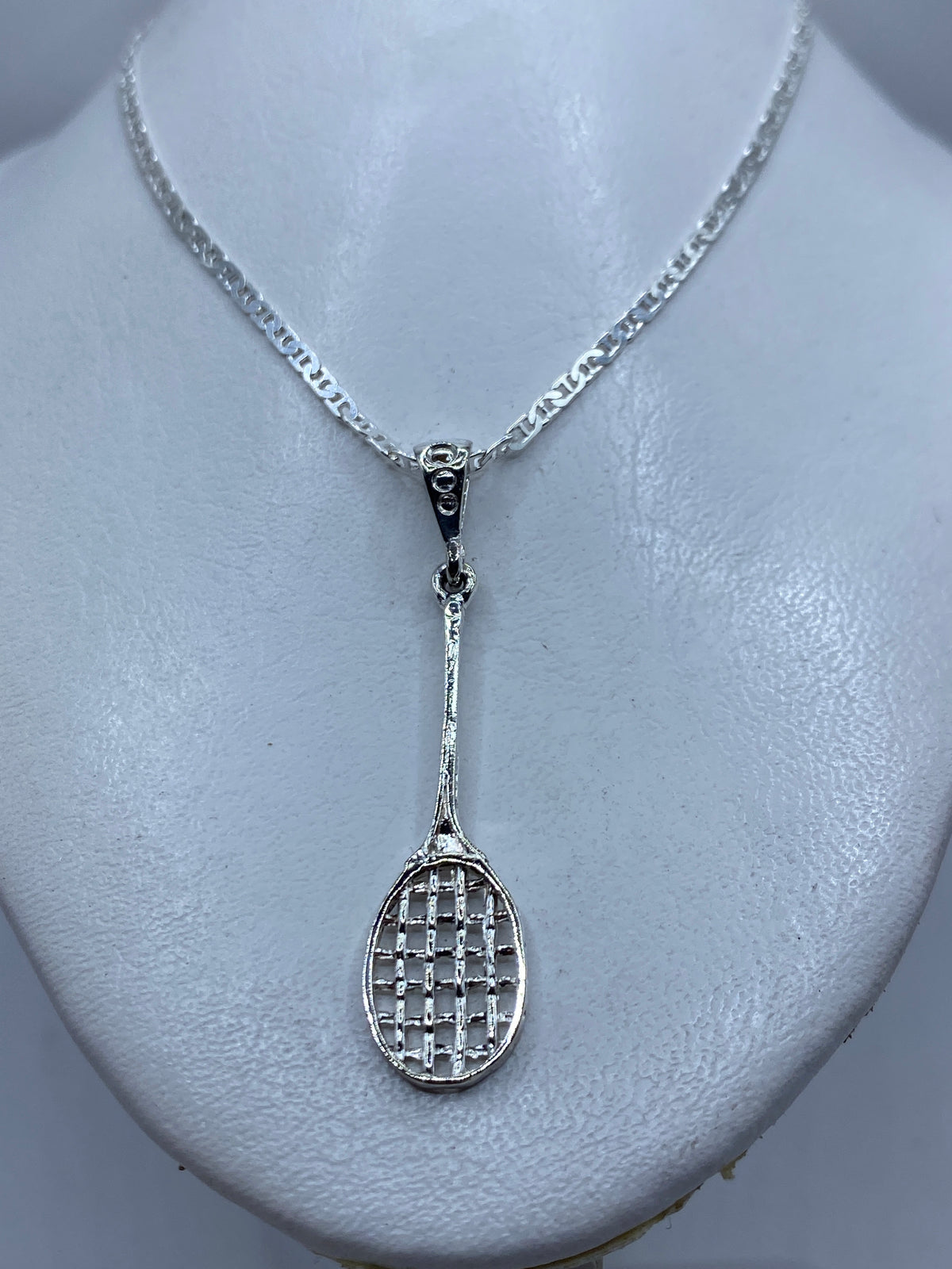 Detalle del calado del dije — diseño de raqueta con hilos de plata y espacios abiertos