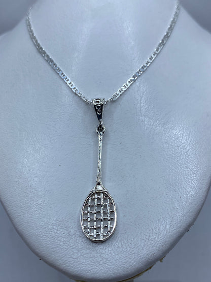 Detalle del calado del dije — diseño de raqueta con hilos de plata y espacios abiertos