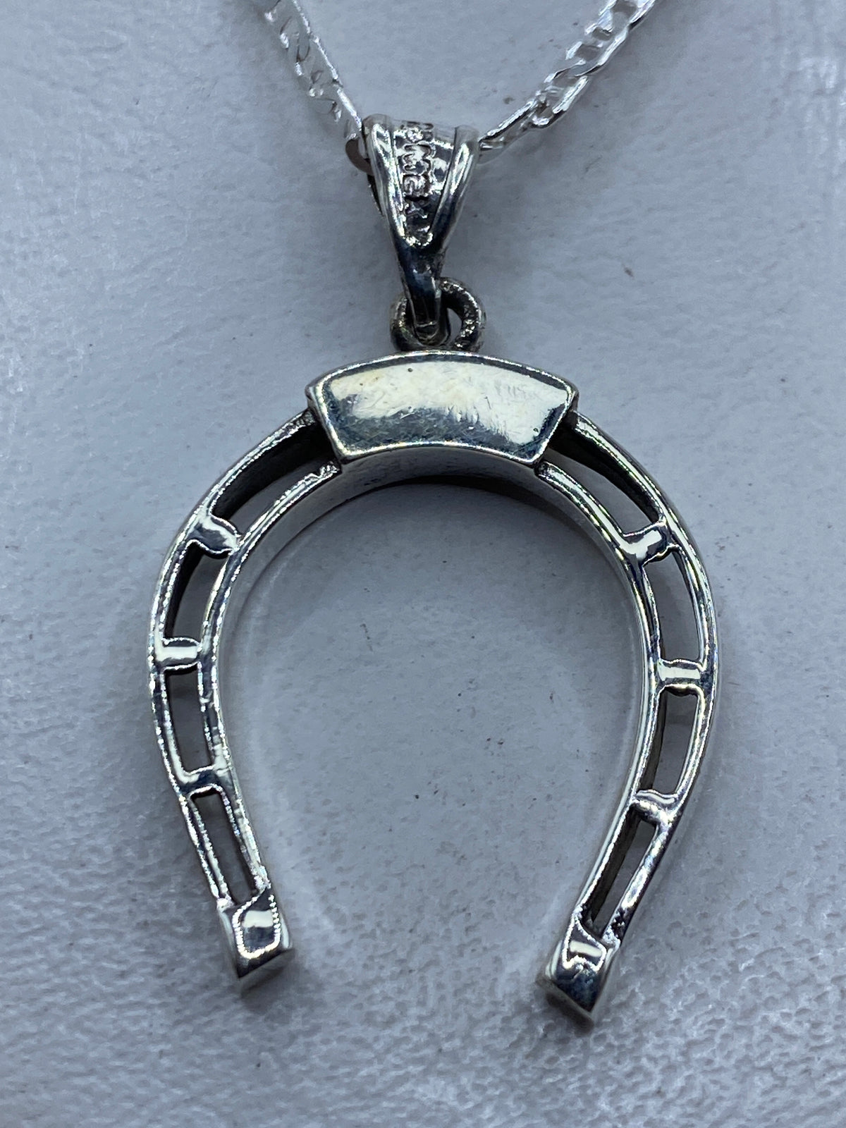 Dije de plata herradura calada de Taxco .925 colgando de cadena plateada