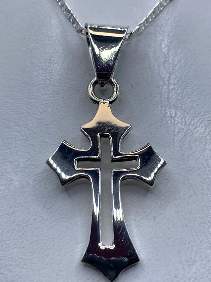 Dije cruz de plata .925 pulida sobre fondo gris, visto desde arriba