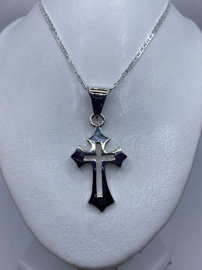 Cruz de plata colgando en cadena plateada, mostrando el diseño cruciforme clásico