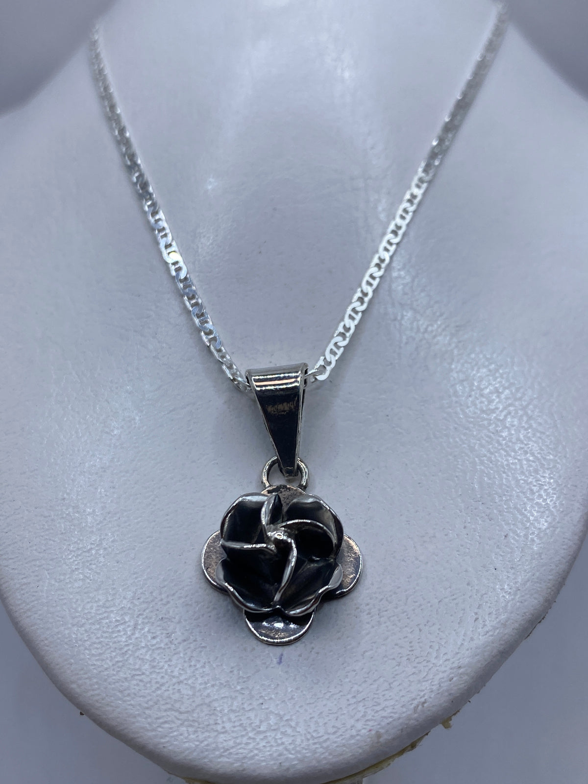Dije floral rosa sobre cadena de plata, llevado al cuello