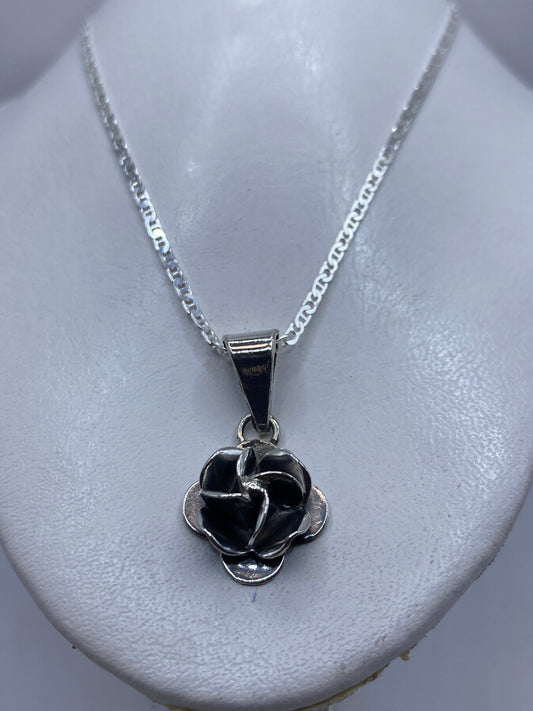 Dije floral rosa sobre cadena de plata, llevado al cuello