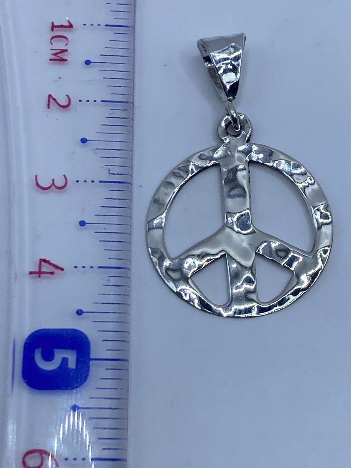 Dije de paz de 4.2 cm en la palma de la mano, escala real