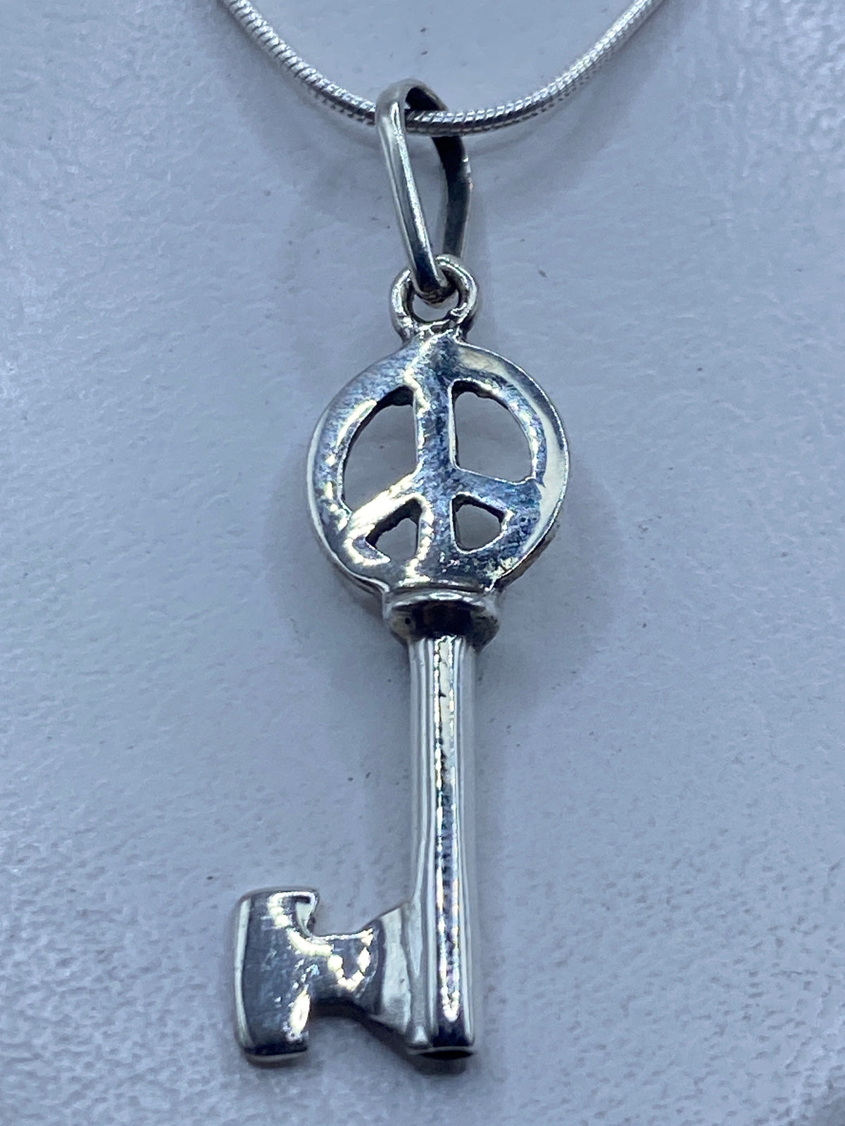 Dije llave de plata .925 en calado con símbolo de paz, 4.7 cm, colgando de cadena plateada