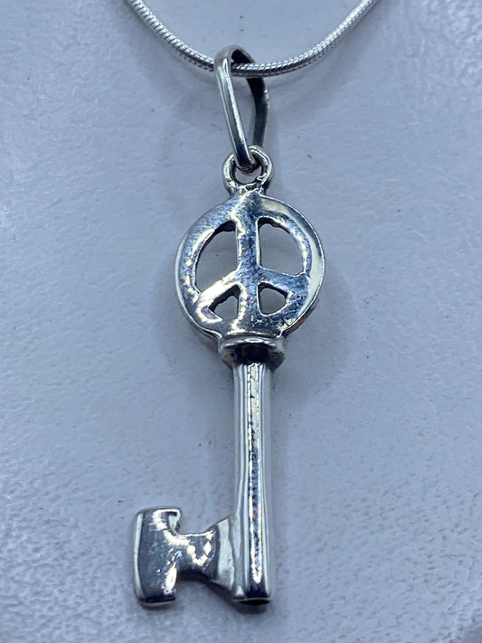 Dije llave de plata .925 en calado con símbolo de paz, 4.7 cm, colgando de cadena plateada
