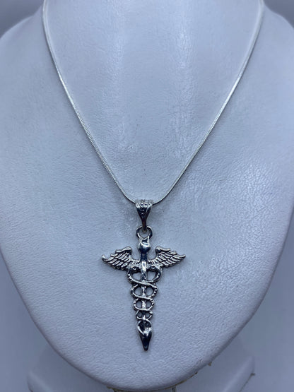 Detalle del Caduceo fundido en plata, con las alas y el bastón con serpientes en alto relieve