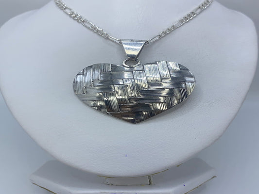 Detalle del relieve en repujado del dije corazón, mostrando el trabajo artesanal