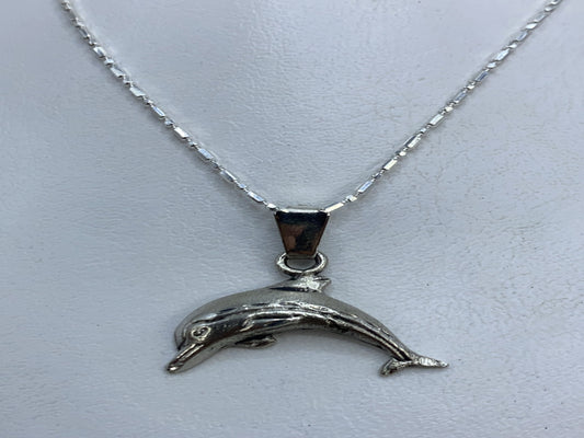 Dije de plata .925 con forma de delfín grabado en relieve, colgando de cadena plateada