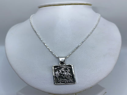 Dije de comunión en plata colocado sobre collar de eslabones