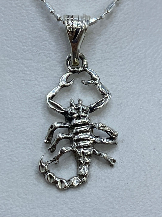 Dije de plata .925 con escorpión en calado, 2 cm de largo, sobre fondo gris