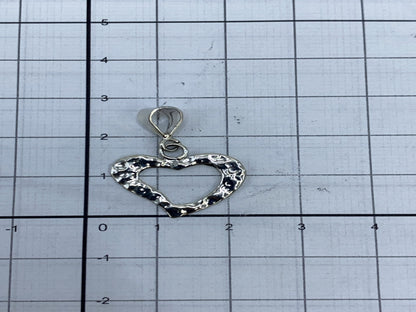 Dije de corazón al lado de regla métrica, midiendo 2 cm de largo