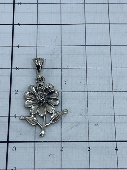 Dije flor de plata vista de frente mostrando textura del repujado