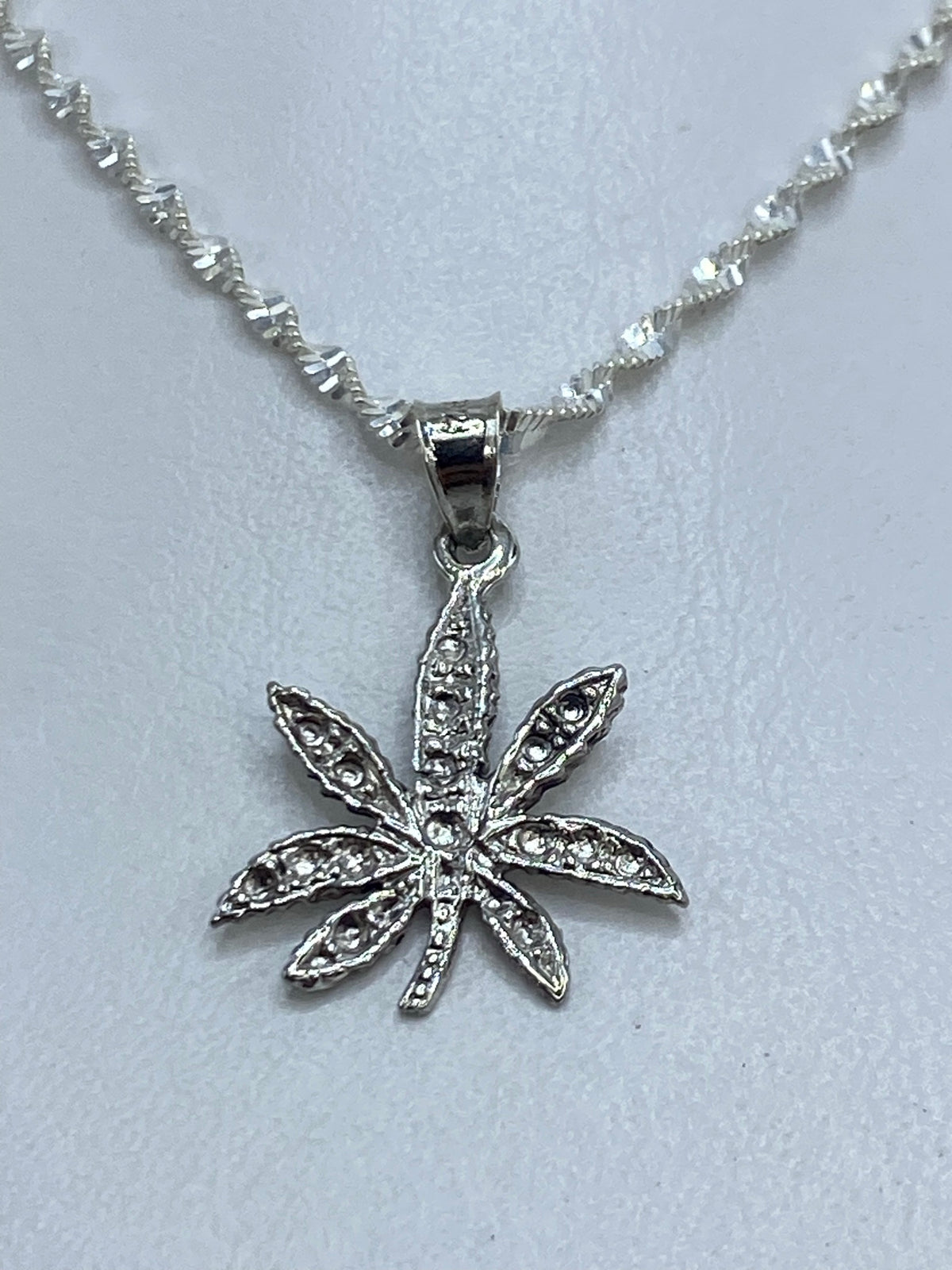 Detalle del repujado a mano: líneas del relieve de la hoja de marihuana en plata .925