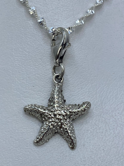 Dije de plata en forma de estrella marina con granulado, colgando de una cadena de plata