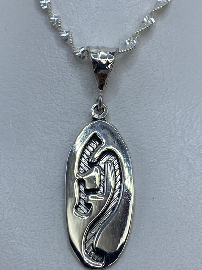 Dije de plata .925 con diseño prehispánico en relieve sobre fondo gris claro