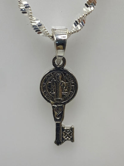 Dije llave de San Benito en plata 925 repujada, medida 2 cm, con cadena plateada