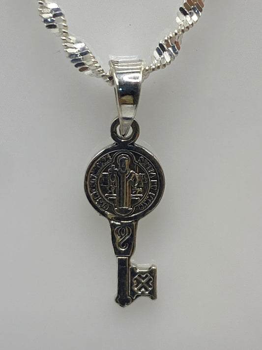 Dije llave de San Benito en plata 925 repujada, medida 2 cm, con cadena plateada