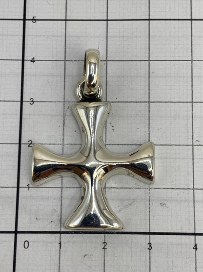 Dije cruz de plata sobre escala de centímetros